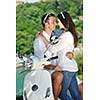 Portrait of happy young love couple on scooter enjoying themselves in a park at summer time