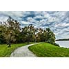 Path in autumn park near the lake with dramatic sky