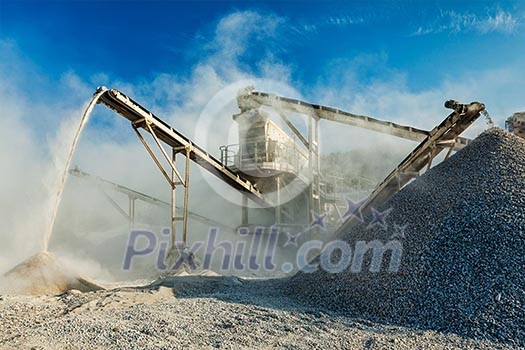 Industrial background - crusher rock stone crushing machine at open pit mining and processing plant for crushed stone, sand and gravel Industrial background - crusher rock stone crushing machine at open pit mining and processing plant for crushed stone, sand and gravel