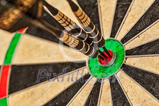 Success hitting target aim goal achievement concept background - three darts in bull's eye close up Success hitting target aim goal achievement concept background - three darts in bull's eye close up