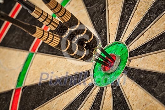 Success hitting target aim goal achievement concept background - three darts in bull's eye close up Success hitting target aim goal achievement concept background - three darts in bull's eye close up