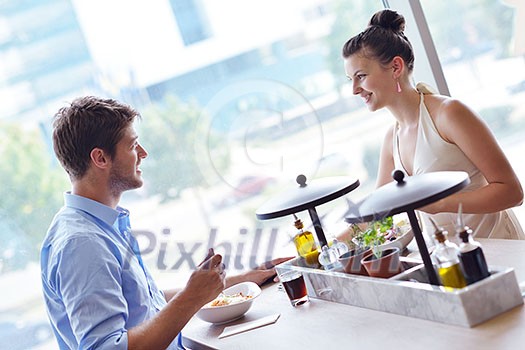 A young couple sitting at a table and have lunch at an outdoor restaurant A young couple sitting at a table and have lunch at an outdoor restaurant