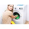 Housework: young woman doing laundry - putting colorful garments into the washing machine (shallow DOF; color toned image)