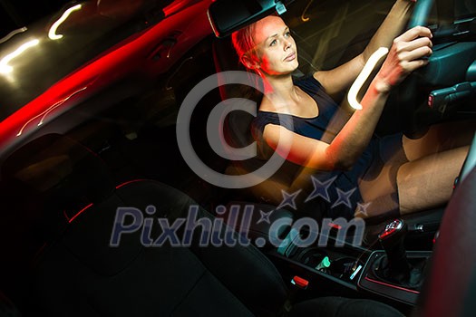 Driving a car at night - pretty, young woman driving her modern car at night, in a city (shallow DOF; color toned image) Driving a car at night - pretty, young woman driving her modern car at night, in a city (shallow DOF; color toned image)