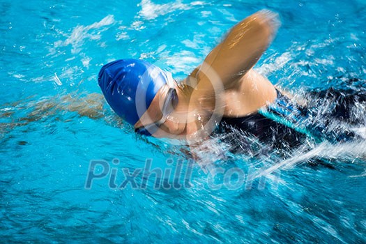 Female swimmer in an indoor swimming pool - doing crawl (shallow DOF) Female swimmer in an indoor swimming pool - doing crawl (shallow DOF)
