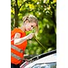 Young female driver wearing a high visibility vest on the roadside after her car has broken down