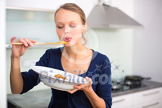 Pretty, young woman cooking a diner in a modern kitchen, tasing the food she made Pretty, young woman cooking a diner in a modern kitchen, tasing the food she made