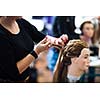 Pretty female hairdresser/haidressing apprentice/student training on an apprentice head