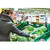 Beautiful, young woman shopping for fruits and vegetables in produce department of a grocery store/supermarket (shallow DOF; color toned image)