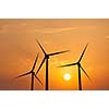 Green renewable energy concept - wind generator turbines in sky on sunset