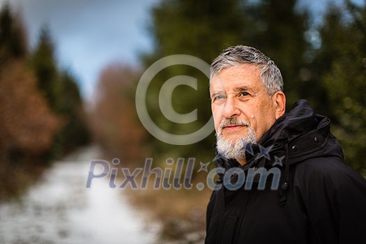 Portrait of a senior man, outdoor on a snowy forest path. Enjoying the crisp fresh air, watching the Sun go down.