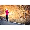 Young woman running outdoors in a city park on a cold fall/winter day