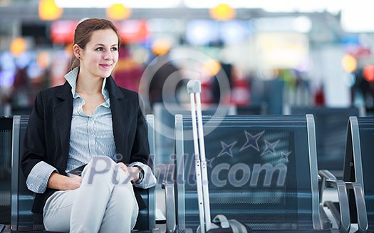 Young female passenger at the airport, using her tablet computer while waiting for her flight (color toned image) Young female passenger at the airport, using her tablet computer while waiting for her flight (color toned image)