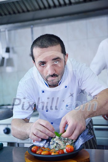Handsome chef dressed in white uniform decorating pasta salad and seafood fish in modern kitchen Handsome chef dressed in white uniform decorating pasta salad and seafood fish in modern kitchen