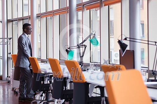 Happy smiling successful African American businessman in a suit in a modern bright office indoors Happy smiling successful African American businessman in a suit in a modern bright office indoors