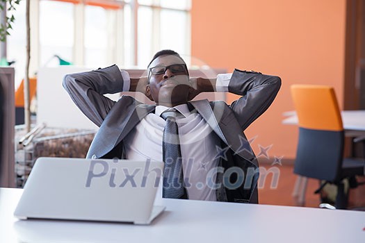Happy smiling successful African American businessman in a suit in a modern bright office indoors Happy smiling successful African American businessman in a suit in a modern bright office indoors