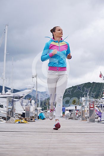 woman jogging at early morning with yacht boats in marina woman jogging at early morning with yacht boats in marina