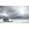 Image of young businessman with mobile phone sitting on floor