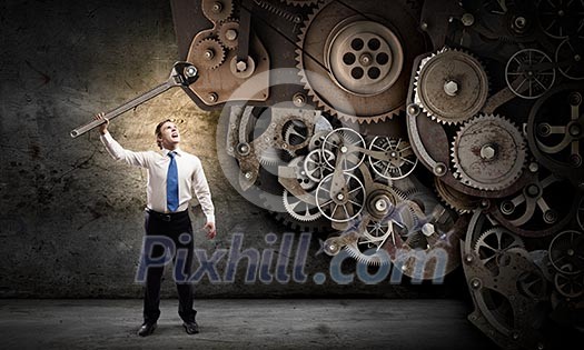 Young businessman fixing gears mechanism with wrench Young businessman fixing gears mechanism with wrench