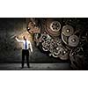 Young businessman fixing gears mechanism with wrench