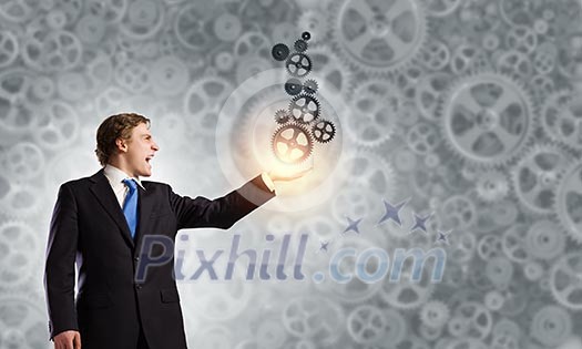 Young businessman carrying cogwheel mechanism in palm Young businessman carrying cogwheel mechanism in palm