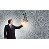 Young businessman carrying cogwheel mechanism in palm