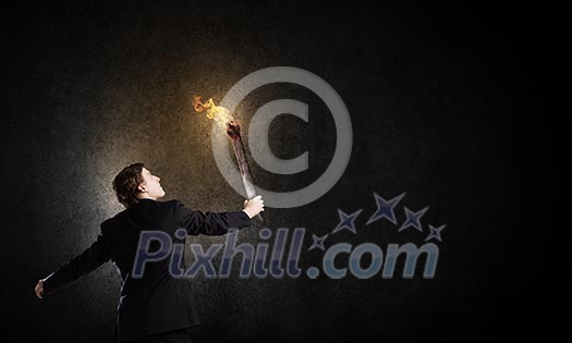 Young businessman holding burning torch in hand Young businessman holding burning torch in hand