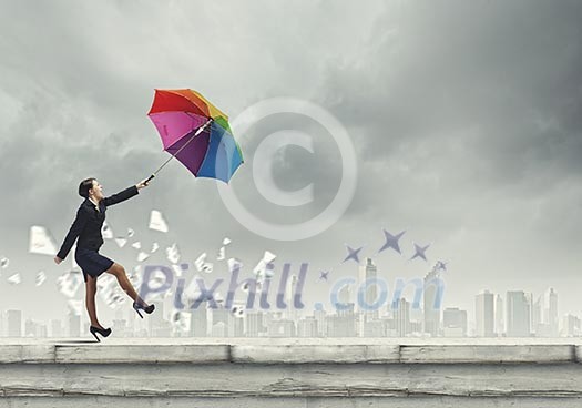 Young businesswoman walking on roof with colorful umbrella Young businesswoman walking on roof with colorful umbrella