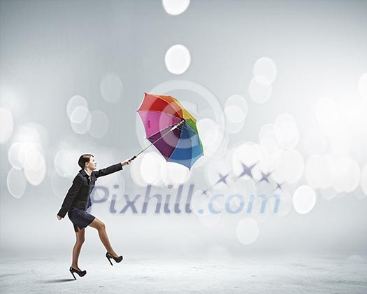 Young businesswoman walking with colorful umbrella against bokeh background Young businesswoman walking with colorful umbrella against bokeh background