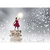 Woman in red dress standing on pile of books