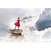Woman in red dress standing on pile of books
