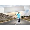 Young man on road holding blank banner. Place for text