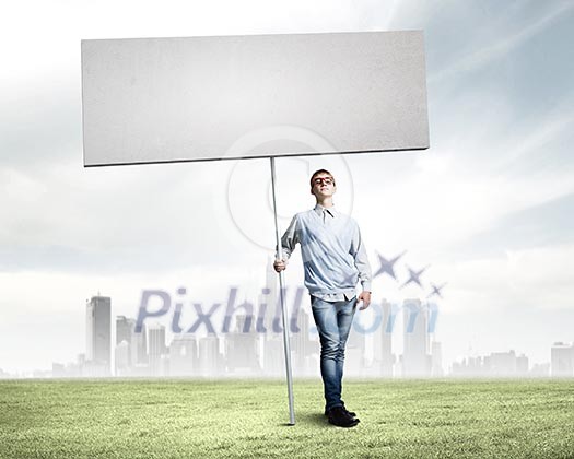 Young man against city background holding blank banner. Place for text Young man against city background holding blank banner. Place for text