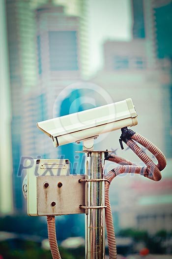 CCTV surveillance camera in Singapore with skyscapers in background CCTV surveillance camera in Singapore with skyscapers in background