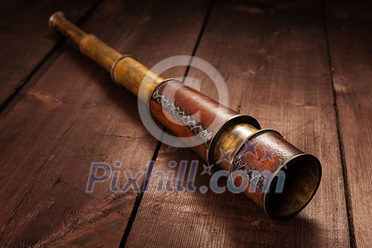 Vintage retro spyglass on wooden background Vintage retro spyglass on wooden background