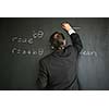 Senior male teacher teaching mathematics, writing on the blackboard