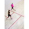 Two female squash players in fast action on a squash court (motion blurred image; color toned image)