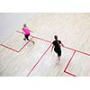 Two female squash players in fast action on a squash court (motion blurred image; color toned image)