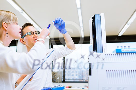 Two young researchers carrying out experiments in a lab (shallow DOF; color toned image) Two young researchers carrying out experiments in a lab (shallow DOF; color toned image)