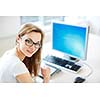 Smiling female student/ businesswoman using her tablet computer and a desktop computer, staying up to date, working, looking at the camera.