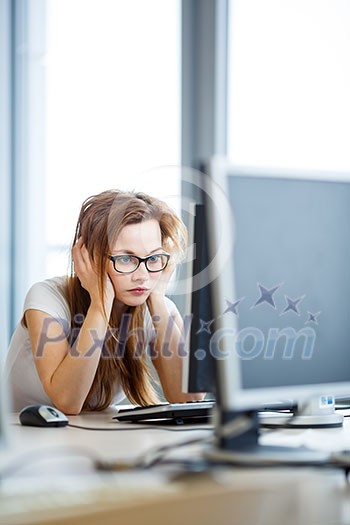 Pretty, female student looking at a desktop computer screen, learning unpleasant news about her exam results. University/office/school concept Pretty, female student looking at a desktop computer screen, learning unpleasant news about her exam results. University/office/school concept