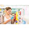 Beautiful young woman shopping for cosmetics in a grocery store/supermarket (color toned image)