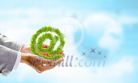 Image of human hand holding plant shaped like at symbol Image of human hand holding plant shaped like at symbol