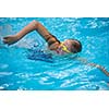Young girl in goggles and cap swimming crawl stroke style in the blue water pool