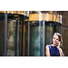 Gorgeous young businesswoman calling on her phone in front of her company's building (shallow DOF; color toned image)