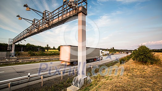 truck passing through a toll gate on a highway (motion blurred image; color toned image) truck passing through a toll gate on a highway (motion blurred image; color toned image)