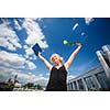 Pretty, young woman celebrating joyfully her graduation - spreading wide her arms, holding her diploma, savouring her success (color toned image; shallow DOF)