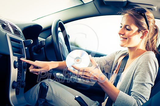 Young female driver playing music in the car (changing CDs) Young female driver playing music in the car (changing CDs)
