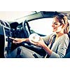 Young female driver playing music in the car (changing CDs)