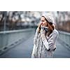 Autumn/winter portrait: young woman dressed in a warm woolen cardigan posing outside in a city park